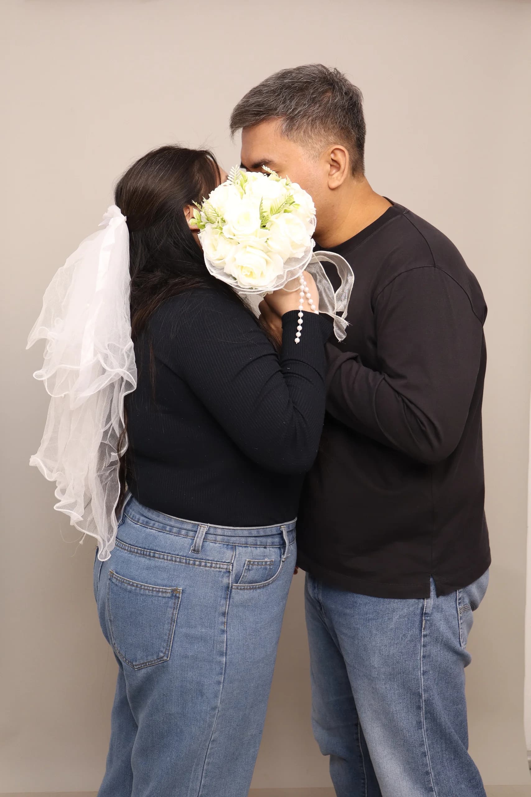 Mario and Inah embracing with a white bouquet between them